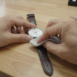 使用後の時計革ベルトを清潔な乾いた布で乾拭きする様子