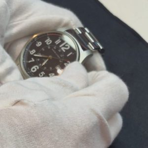 中古時計のリューズを操作して時刻合わせや針送りを確認する様子